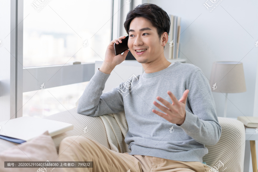 年轻男子坐在沙发上打电话