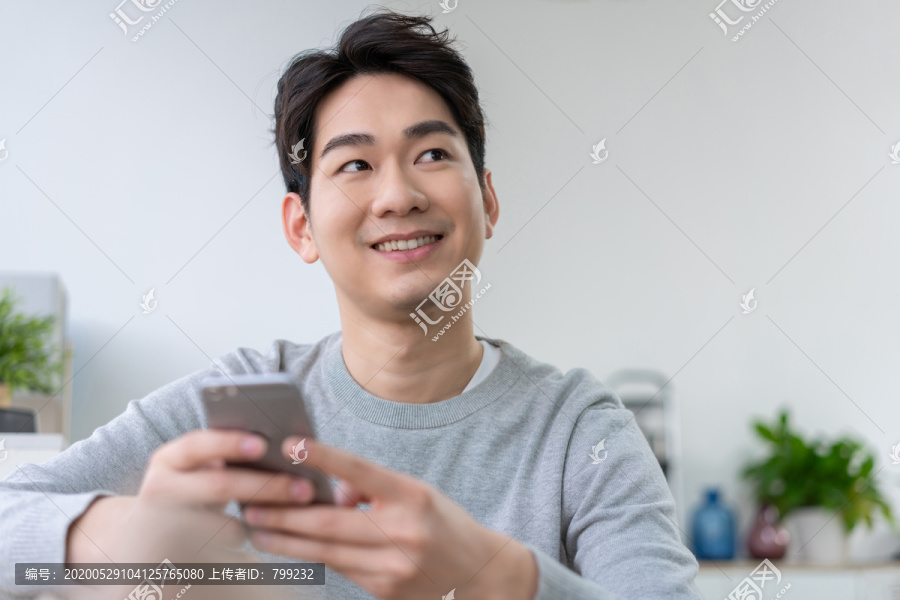 年轻男子坐在沙发上使用手机