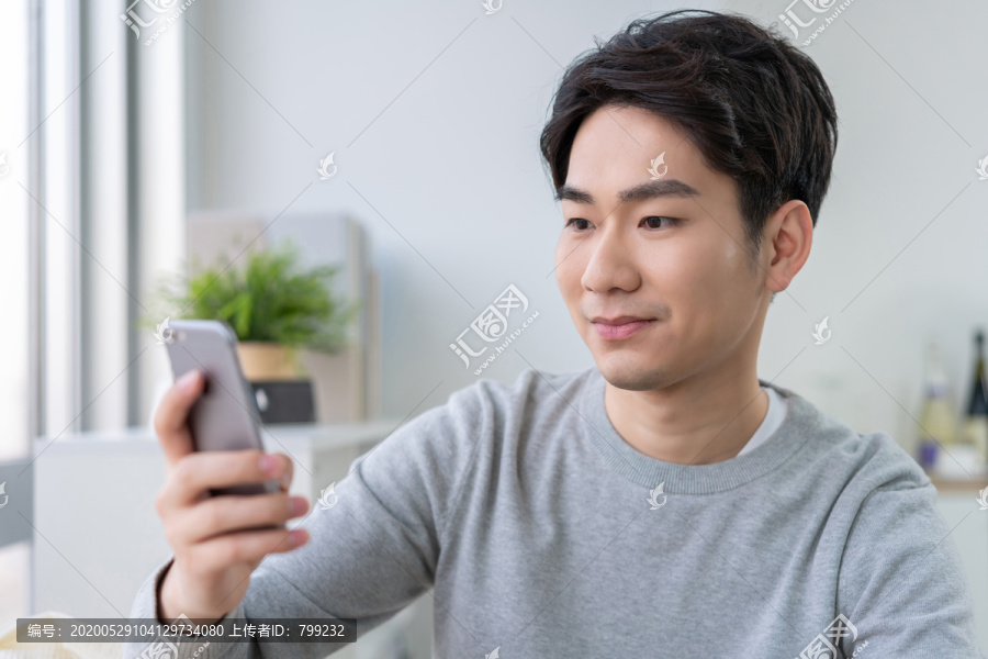 年轻男子坐在沙发上使用手机
