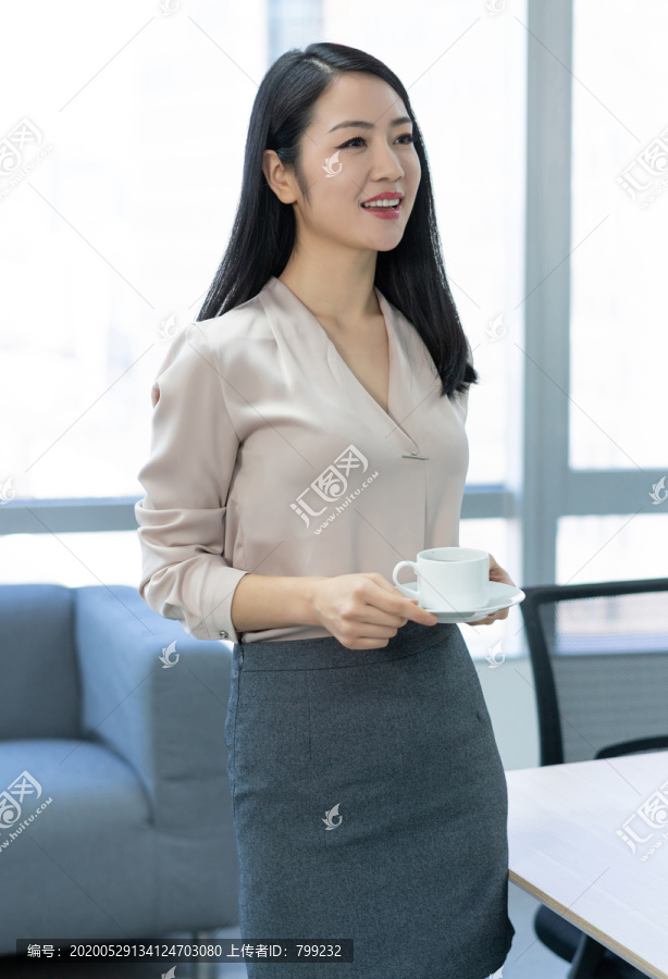年轻商务女士在办公室喝咖啡