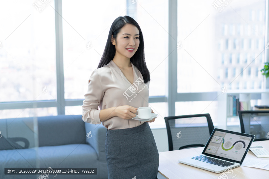 年轻商务女士在办公室喝咖啡