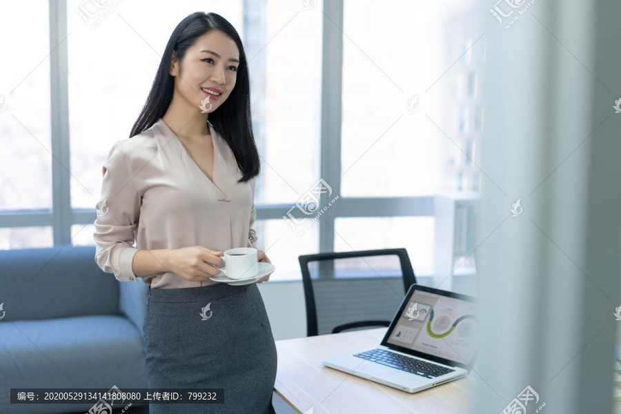 年轻商务女士在办公室喝咖啡
