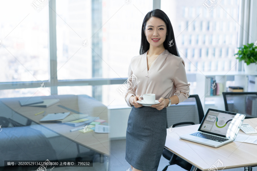 年轻商务女士在办公室喝咖啡