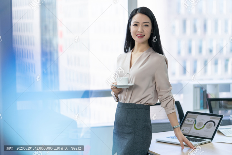 年轻商务女士在办公室喝咖啡