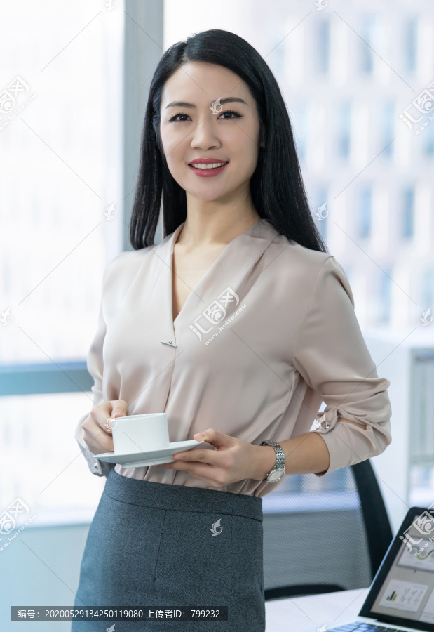 年轻商务女士在办公室喝咖啡