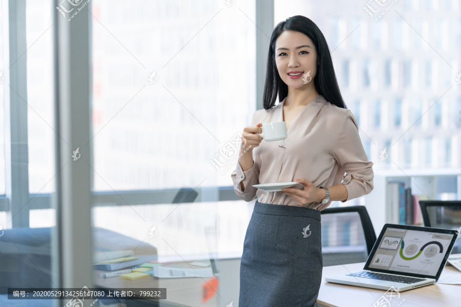 年轻商务女士在办公室喝咖啡