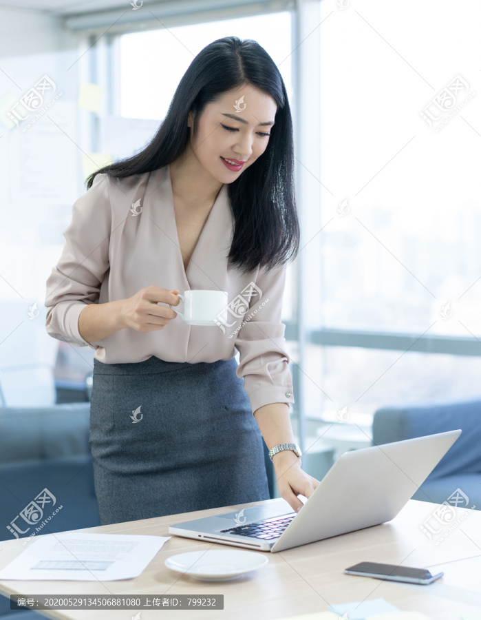 年轻商务女士在办公室喝咖啡