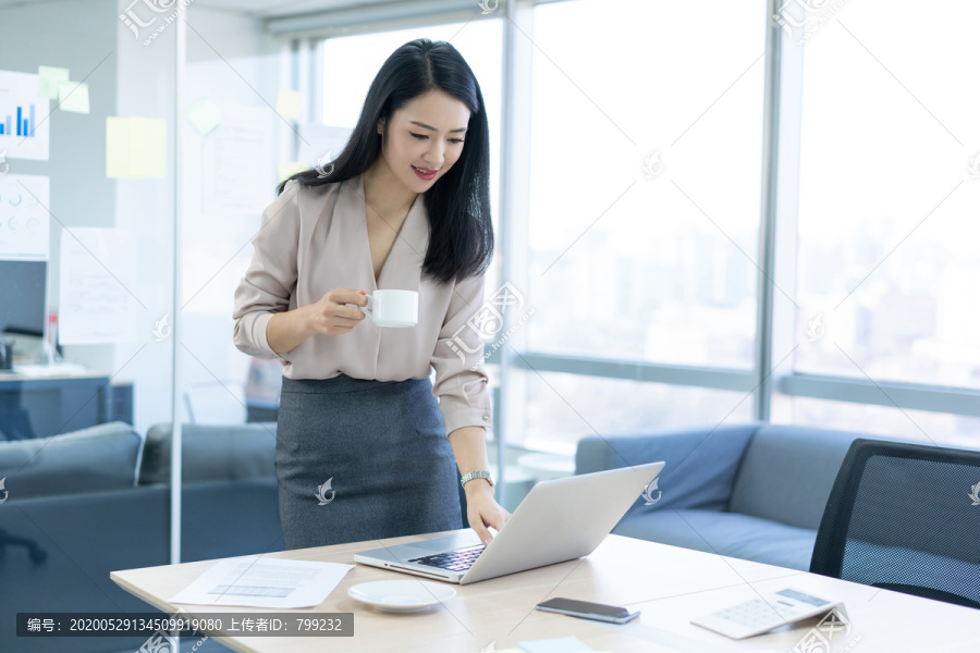 年轻商务女士在办公室喝咖啡