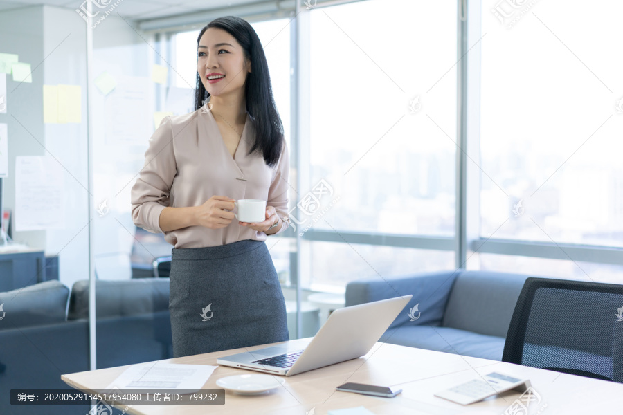 年轻商务女士在办公室喝咖啡