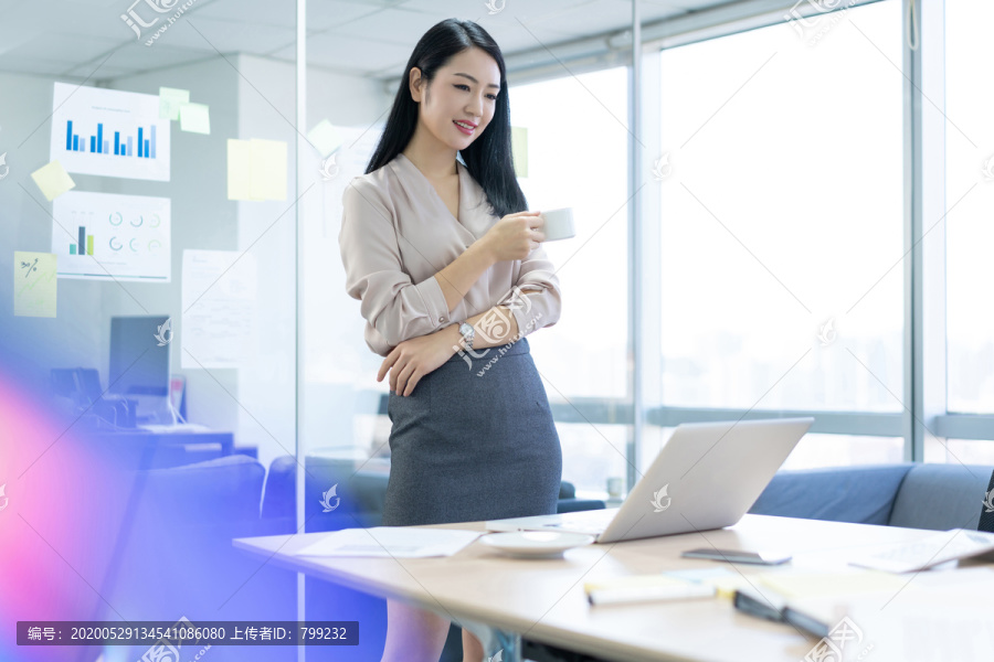 年轻商务女士在办公室喝咖啡