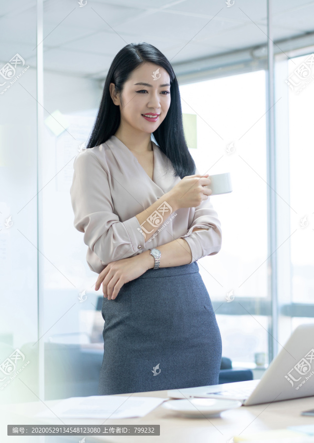 年轻商务女士在办公室喝咖啡