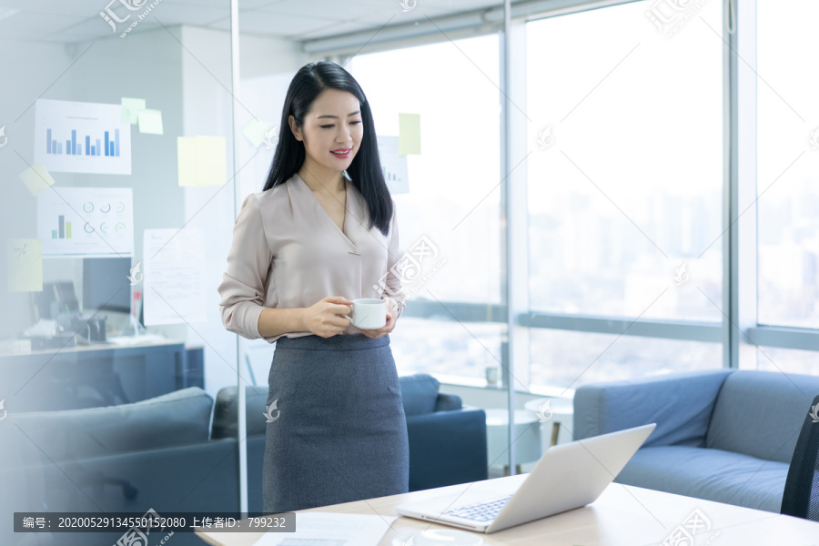 年轻商务女士在办公室喝咖啡