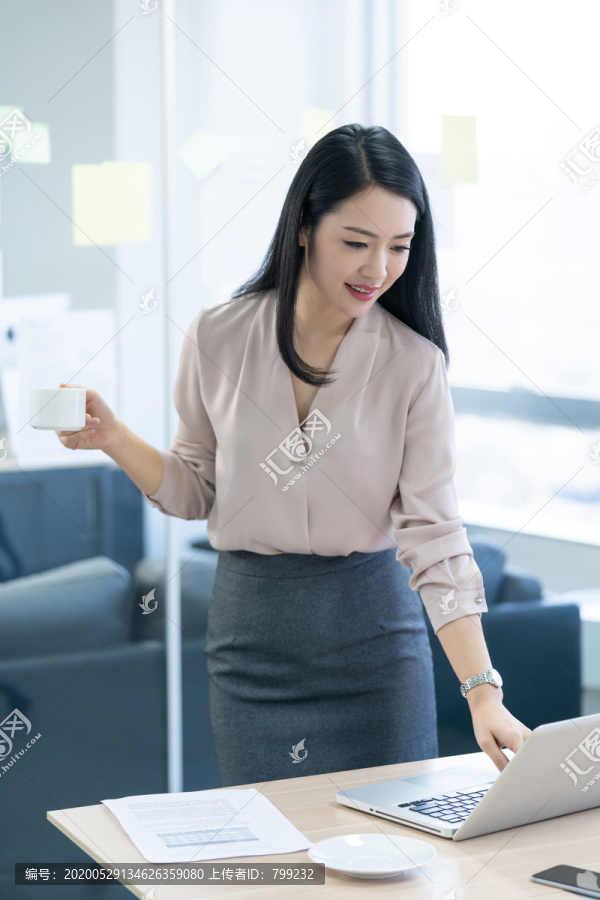 年轻商务女士在办公室喝咖啡