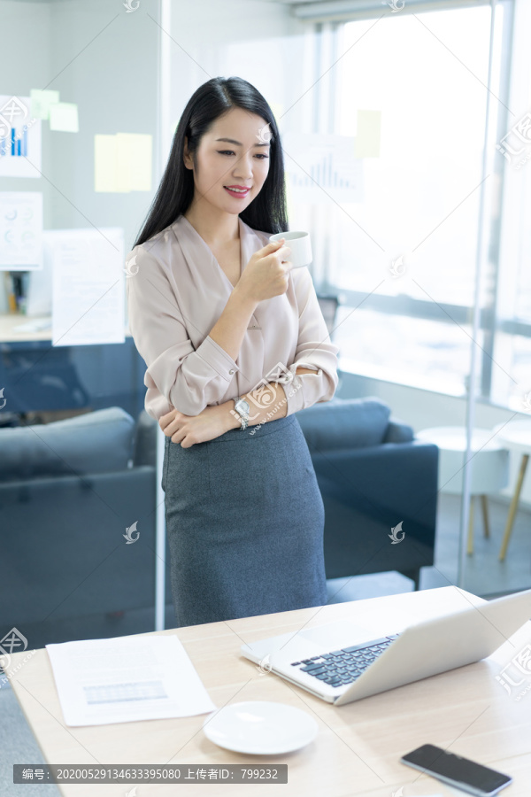 年轻商务女士在办公室喝咖啡