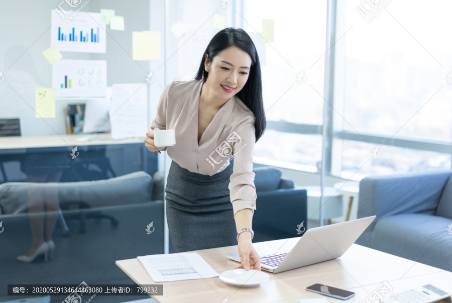 年轻商务女士在办公室喝咖啡