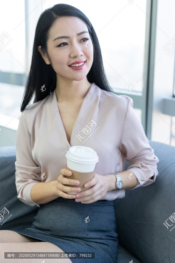 年轻商务女士在办公室喝咖啡