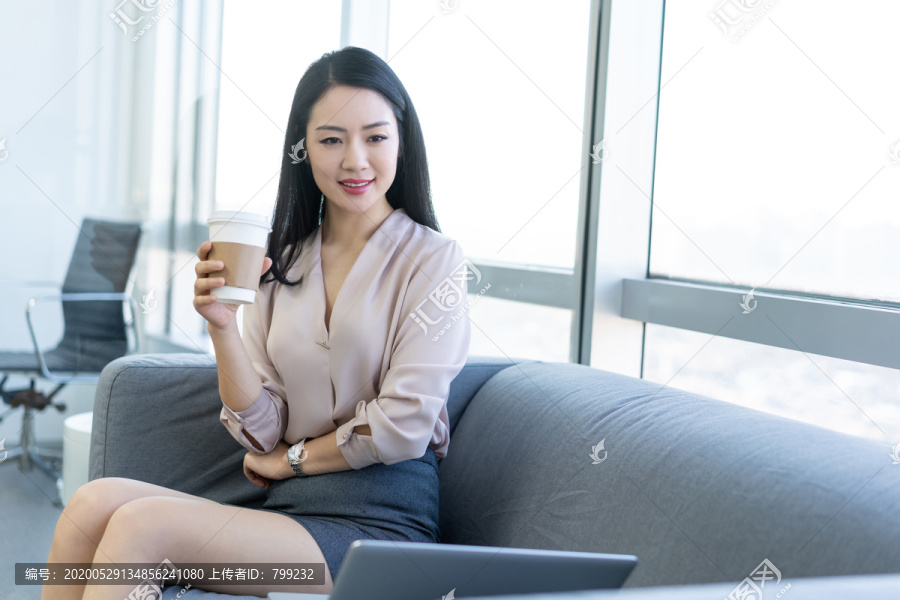 年轻商务女士在办公室喝咖啡