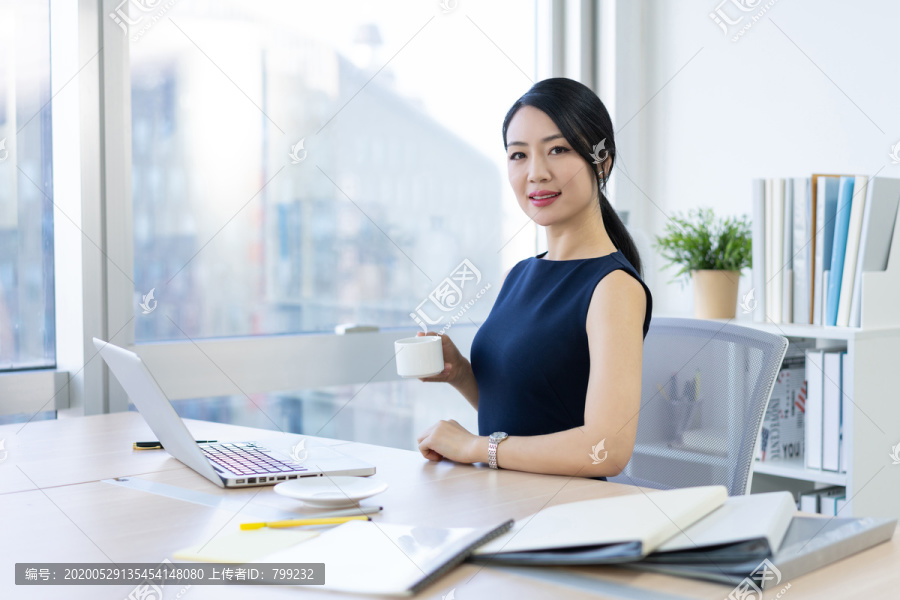 年轻商务女士在办公室喝咖啡