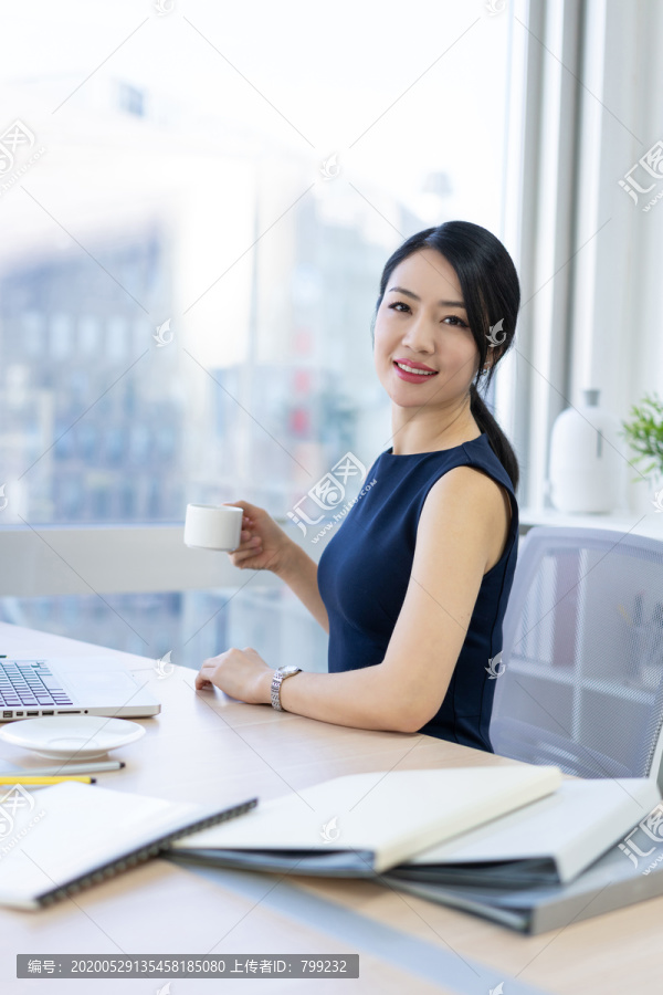 年轻商务女士在办公室喝咖啡