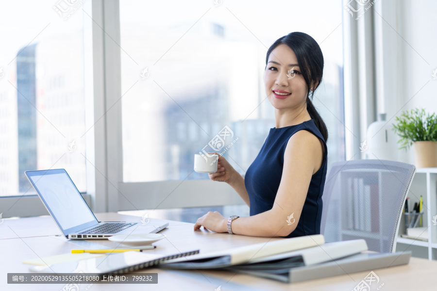 年轻商务女士在办公室喝咖啡