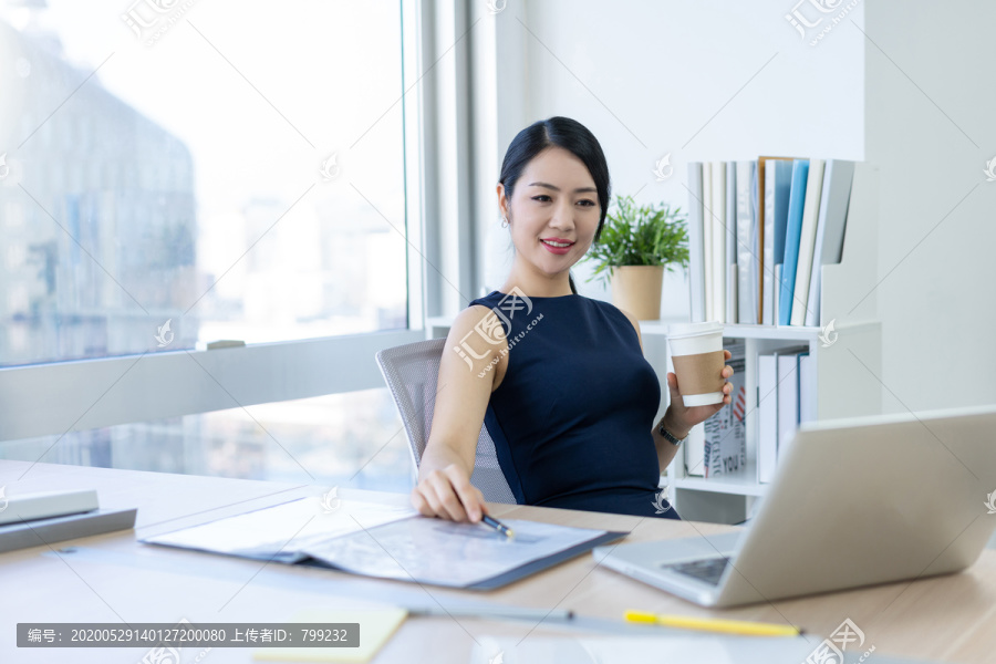 年轻商务女士在办公室喝咖啡