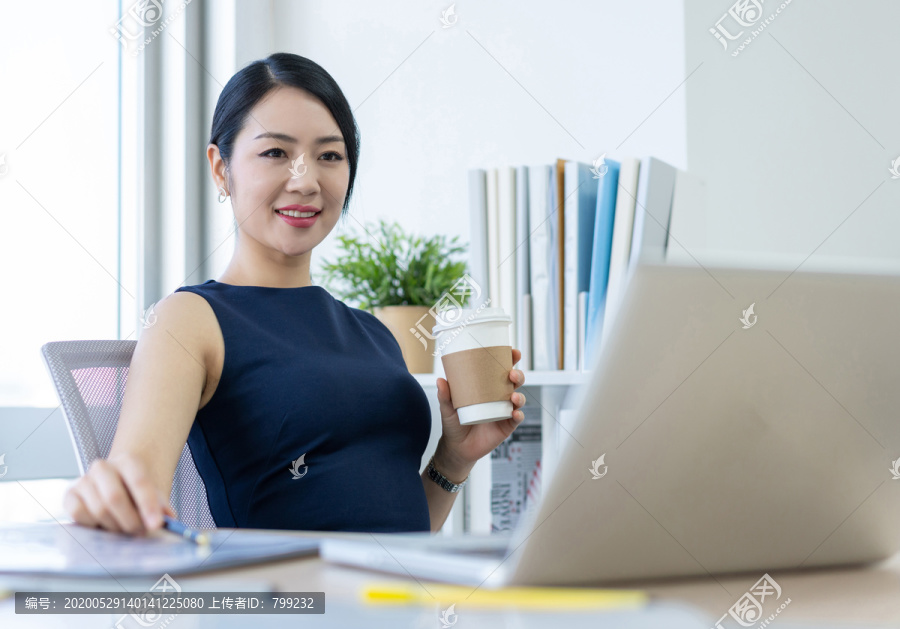 年轻商务女士在办公室喝咖啡