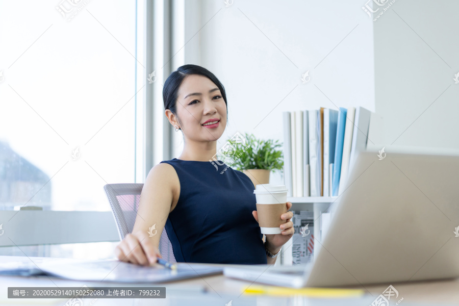 年轻商务女士在办公室喝咖啡
