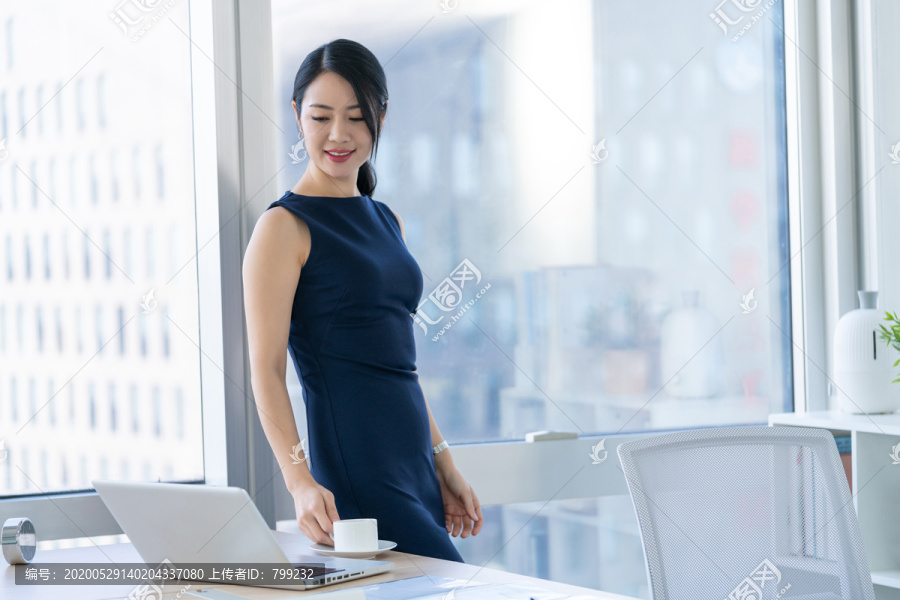 年轻商务女士在办公室喝咖啡