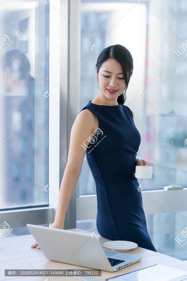 年轻商务女士在办公室喝咖啡