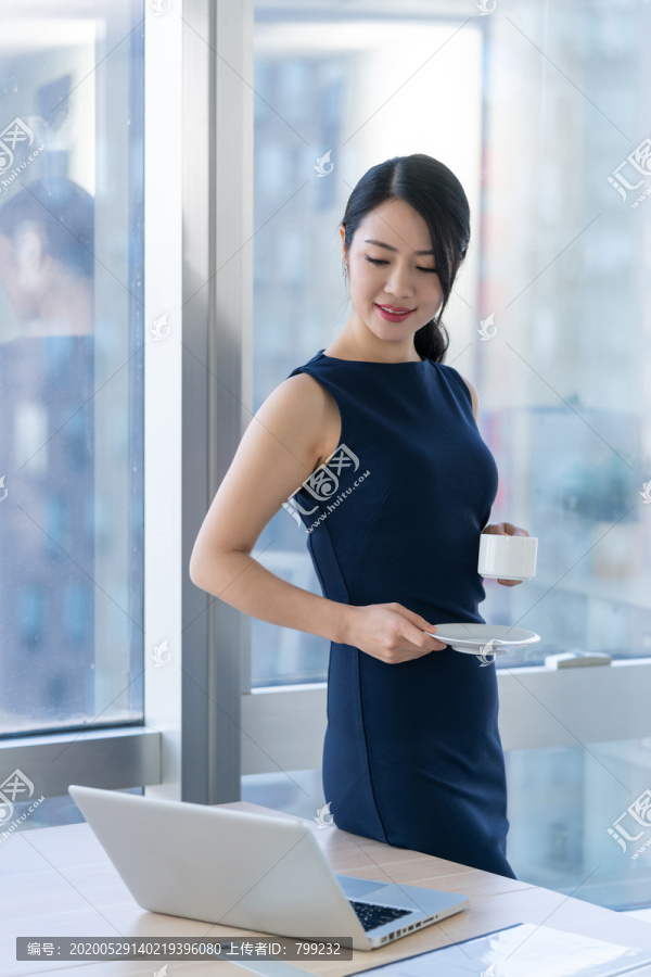 年轻商务女士在办公室喝咖啡