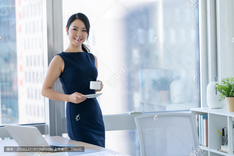 年轻商务女士在办公室喝咖啡