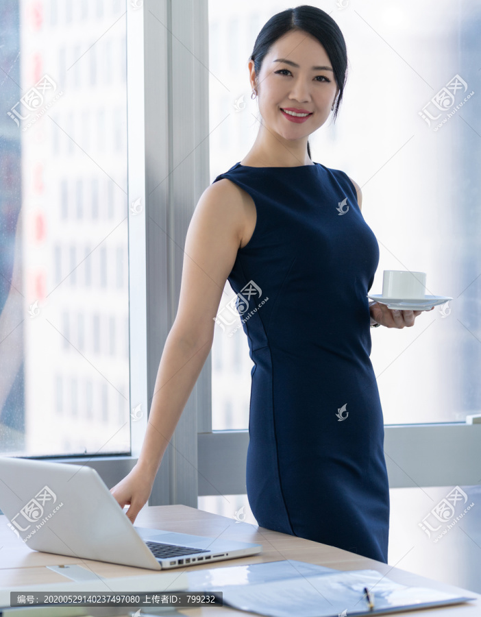 年轻商务女士在办公室喝咖啡