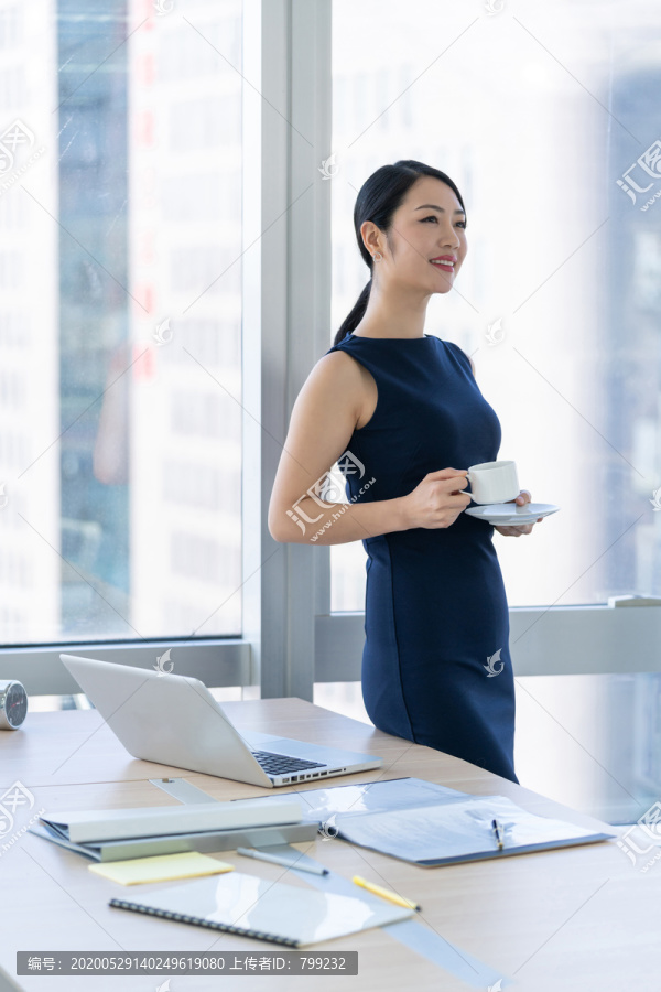 年轻商务女士在办公室喝咖啡