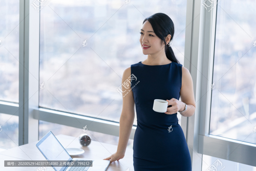 年轻商务女士在办公室喝咖啡