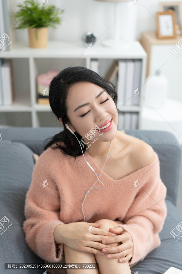 年轻女子坐在沙发上听音乐