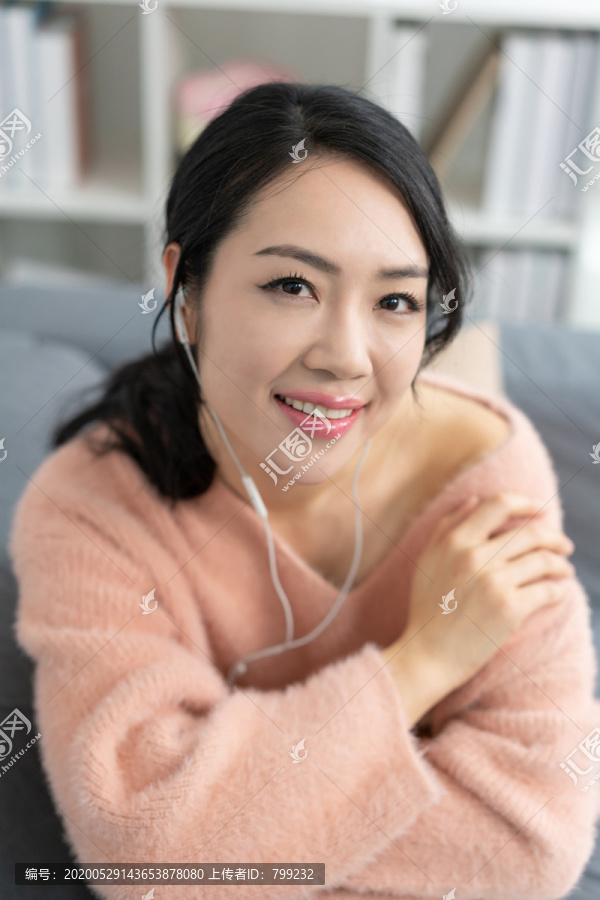 年轻女子坐在沙发上听音乐