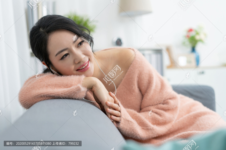 年轻女子坐在沙发上听音乐