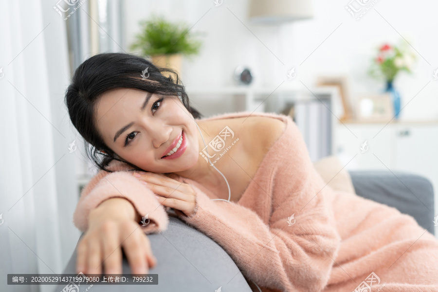 年轻女子坐在沙发上听音乐