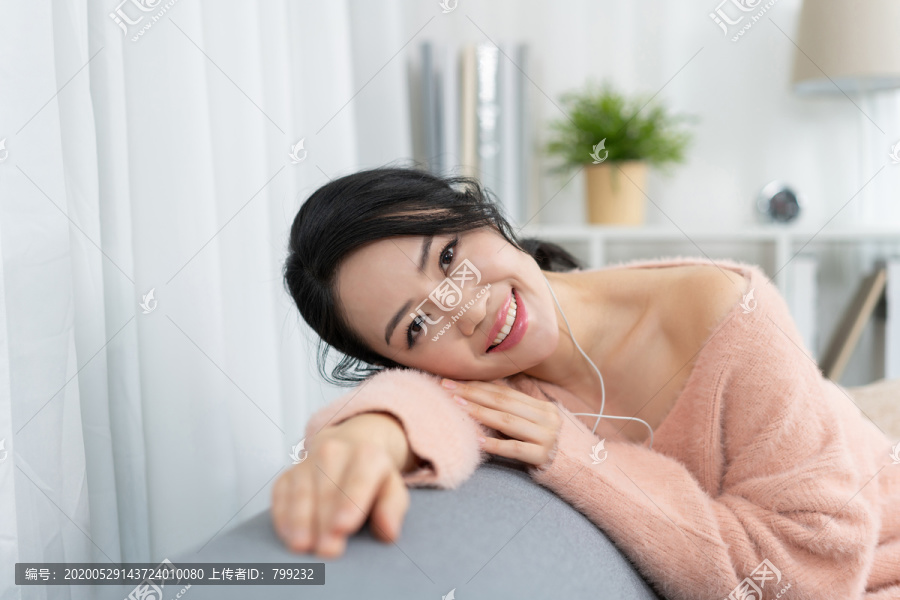 年轻女子坐在沙发上听音乐