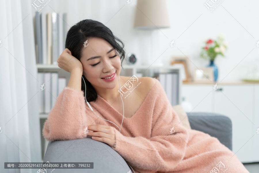 年轻女子坐在沙发上听音乐