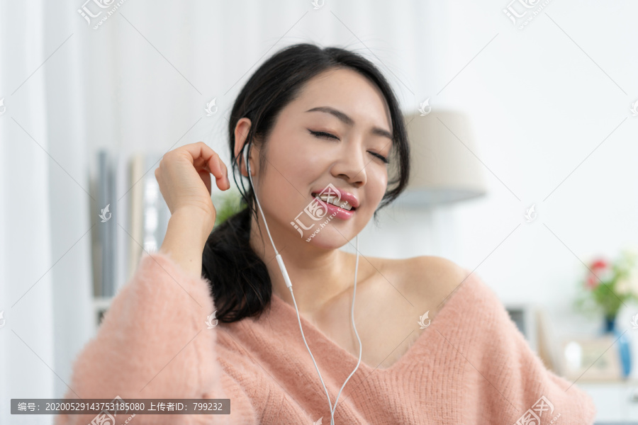 年轻女子坐在沙发上听音乐