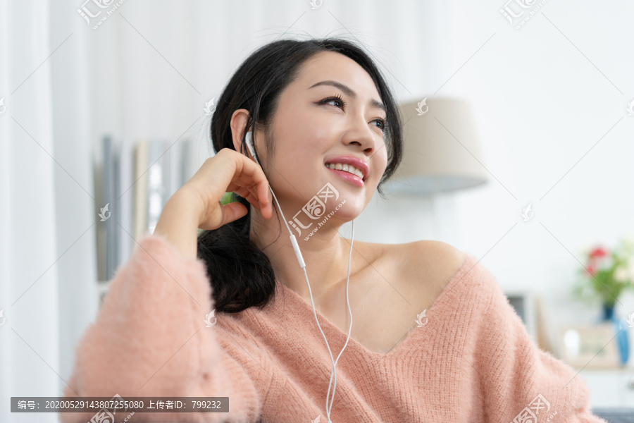年轻女子坐在沙发上听音乐