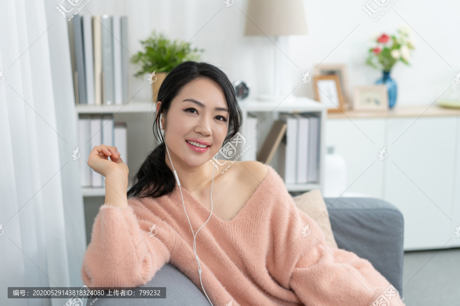 年轻女子坐在沙发上听音乐