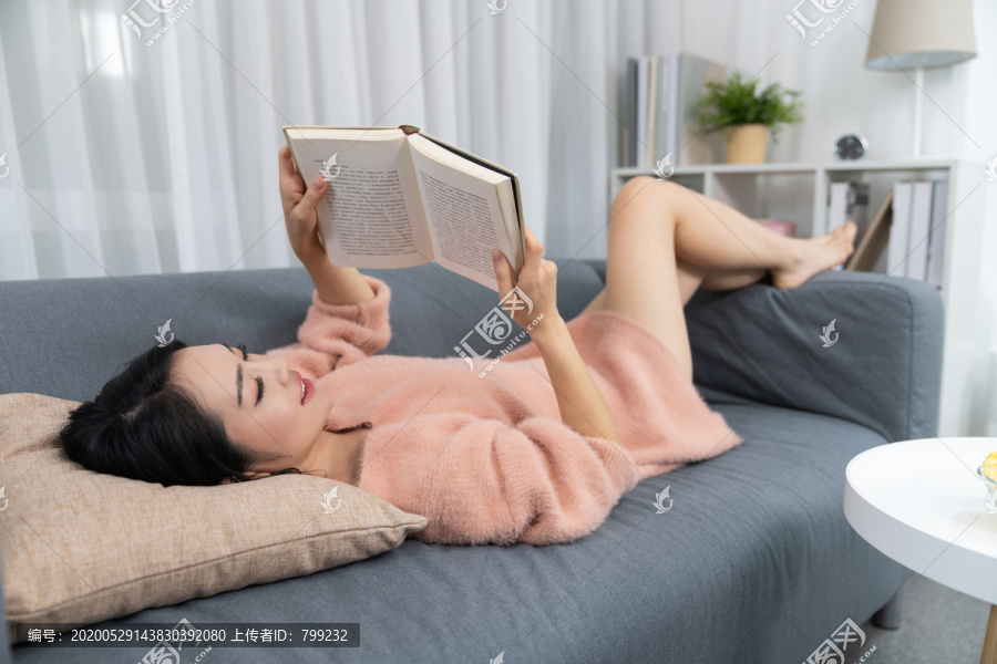 年轻女子躺在沙发上看书