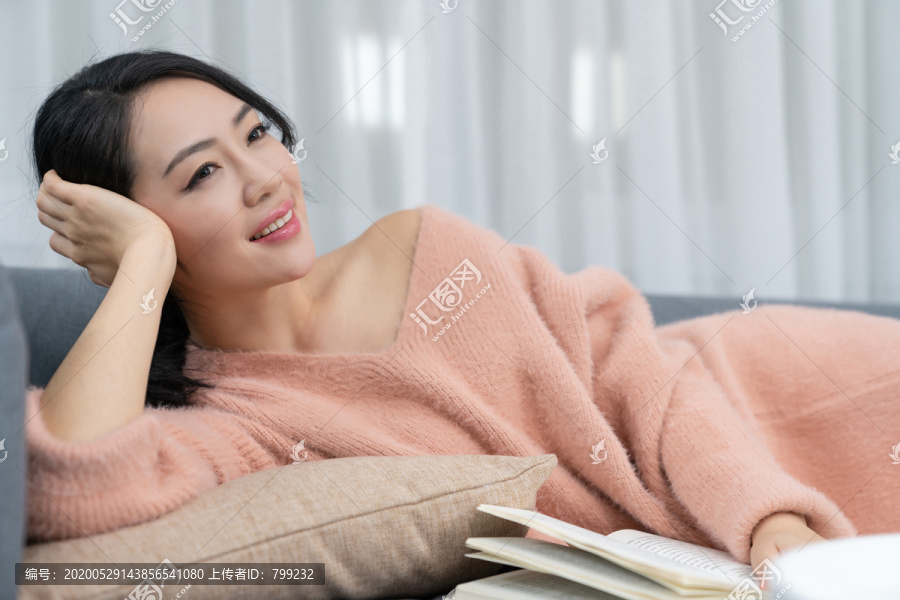 年轻女子躺在沙发上看书