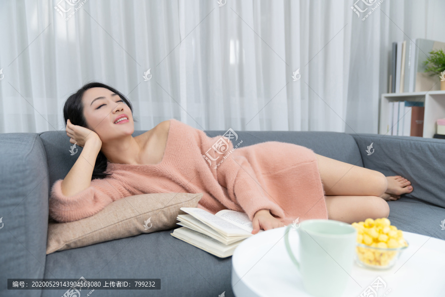 年轻女子躺在沙发上看书