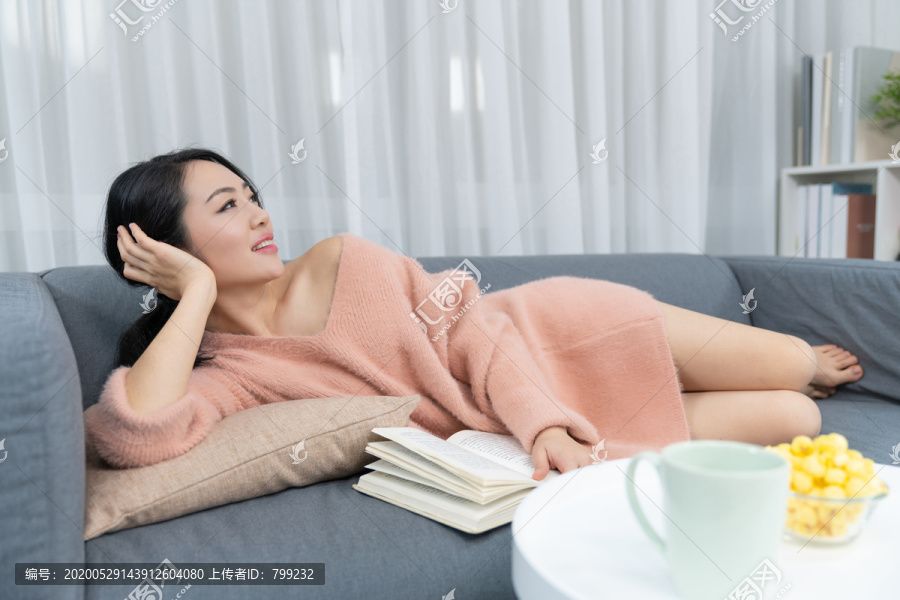 年轻女子躺在沙发上看书