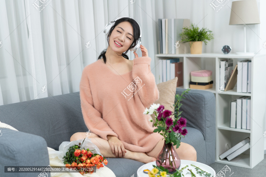 年轻女子坐在沙发上听音乐