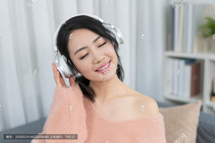 年轻女子坐在沙发上听音乐