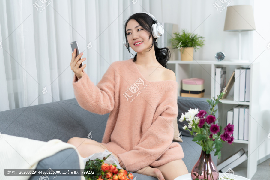 年轻女子坐在沙发上听音乐